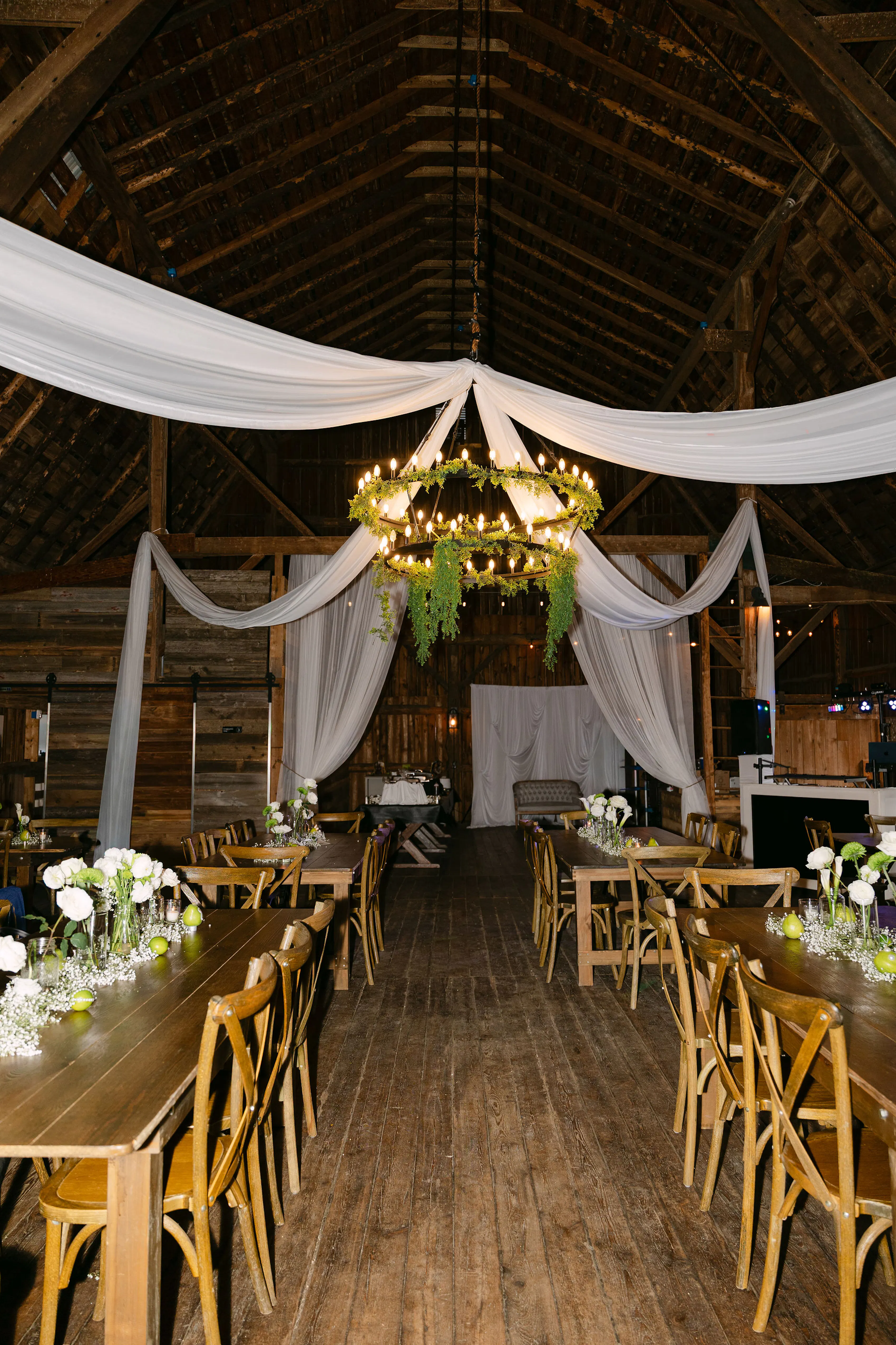 Barn wedding reception setup and decor with fabric drapery and calla lillies