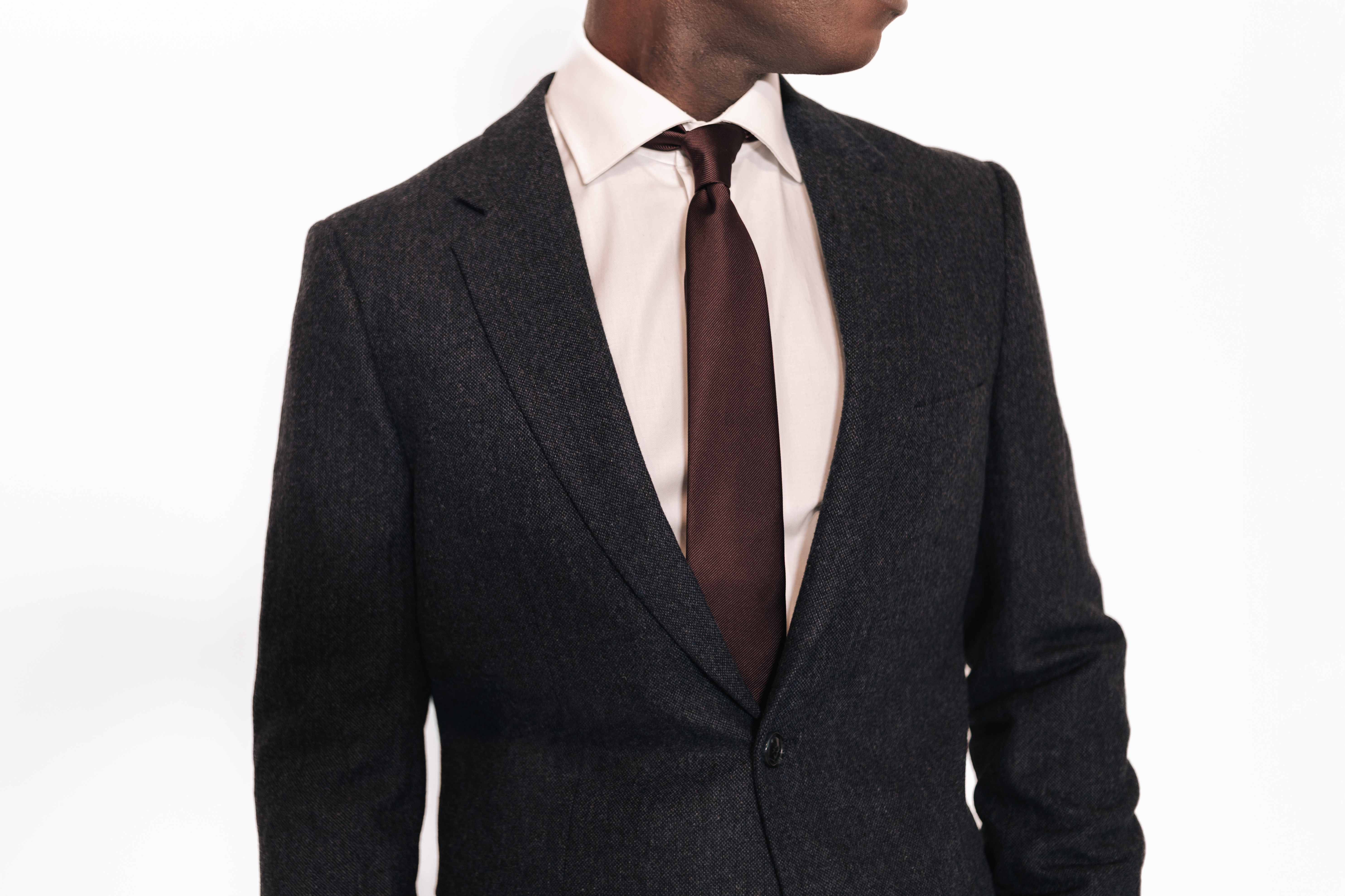 Close-up of a the chest of a man in a full suit against a white background.