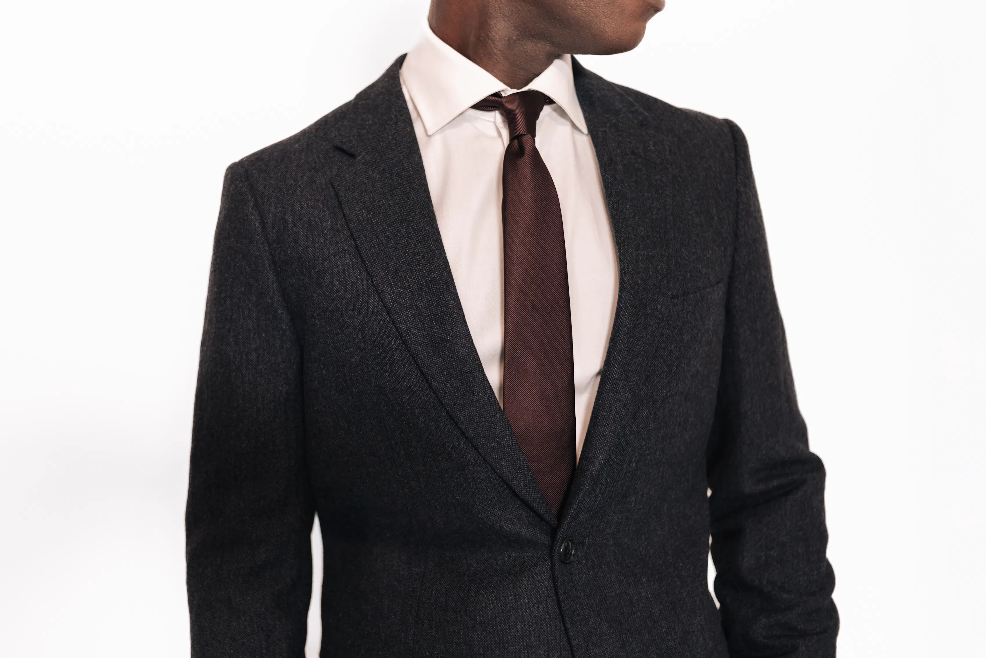 Close-up of a the chest of a man in a full suit against a white background.