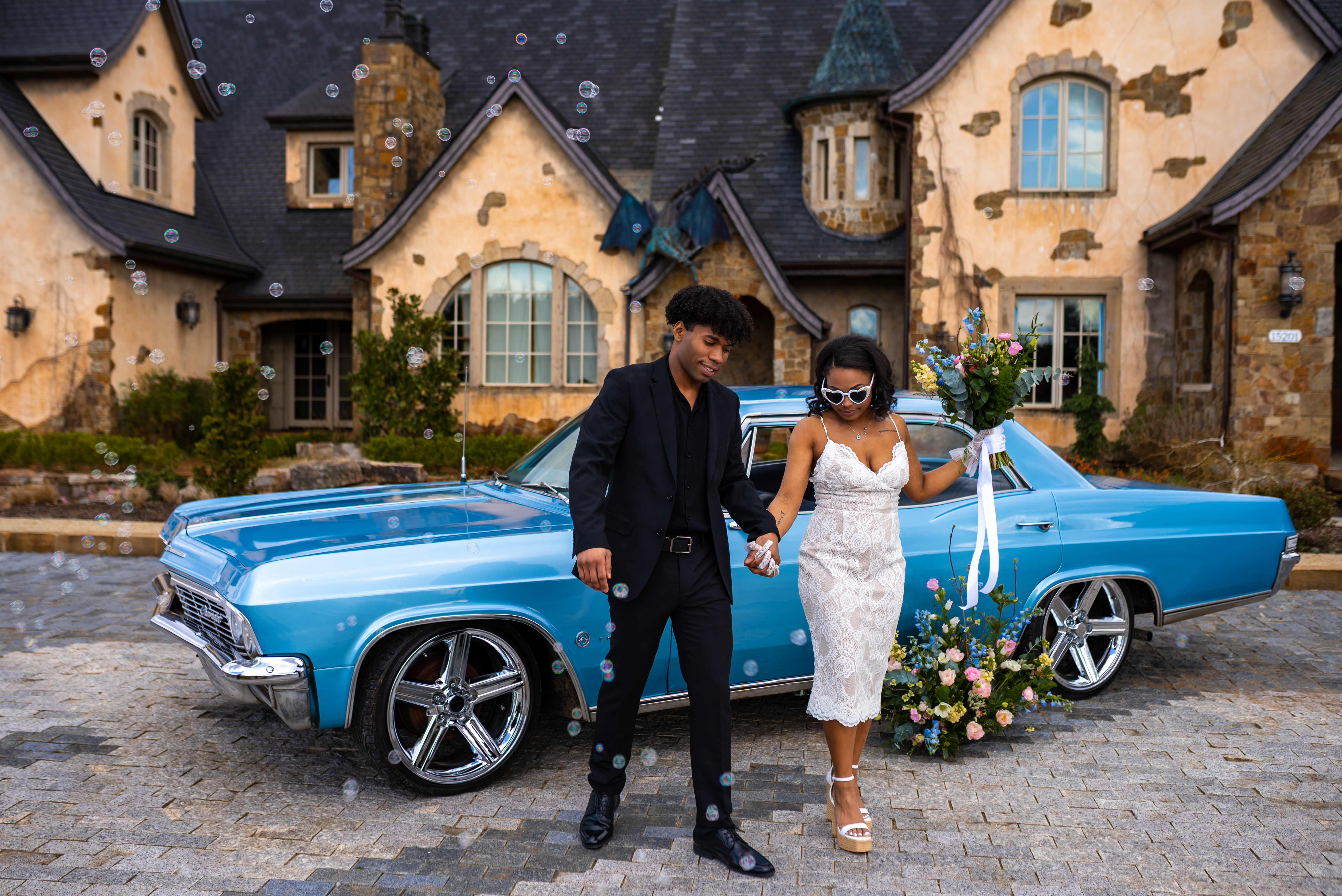 A teenage guy and his date stepping out of a blue car in a residential area.