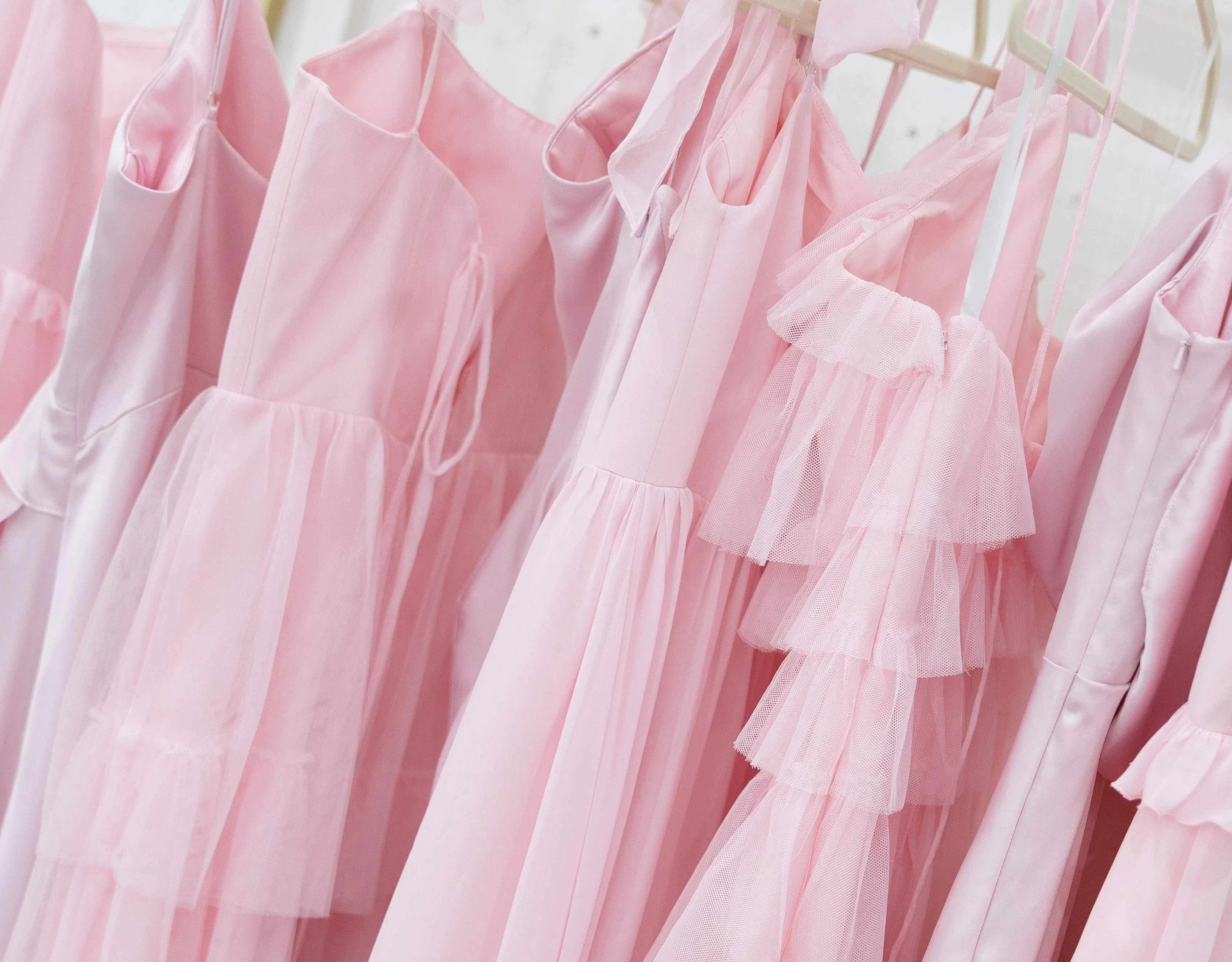 Close-up of 6 pink bridesmaids dresses on a rack.
