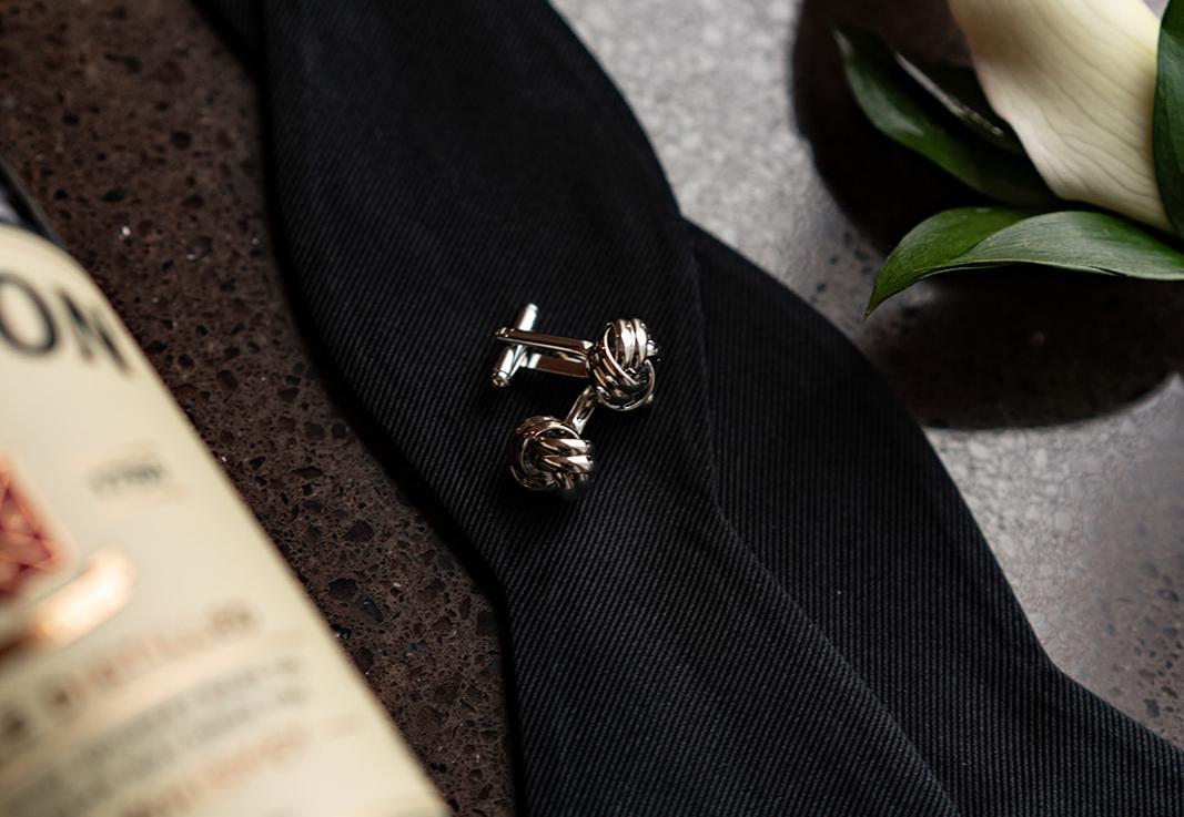 Closeup of cufflinks laying on a tuxedo jacket.