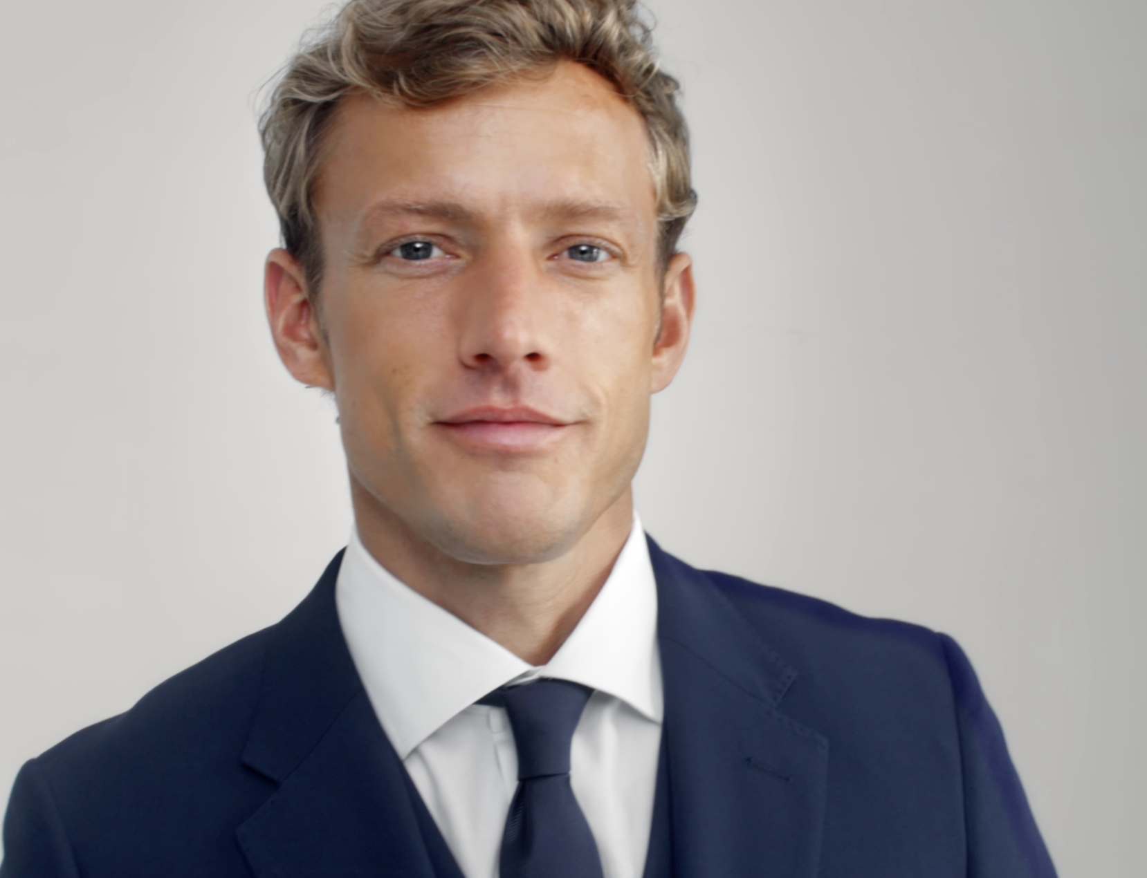 Up close of a man wearing a navy tie with a navy suit.