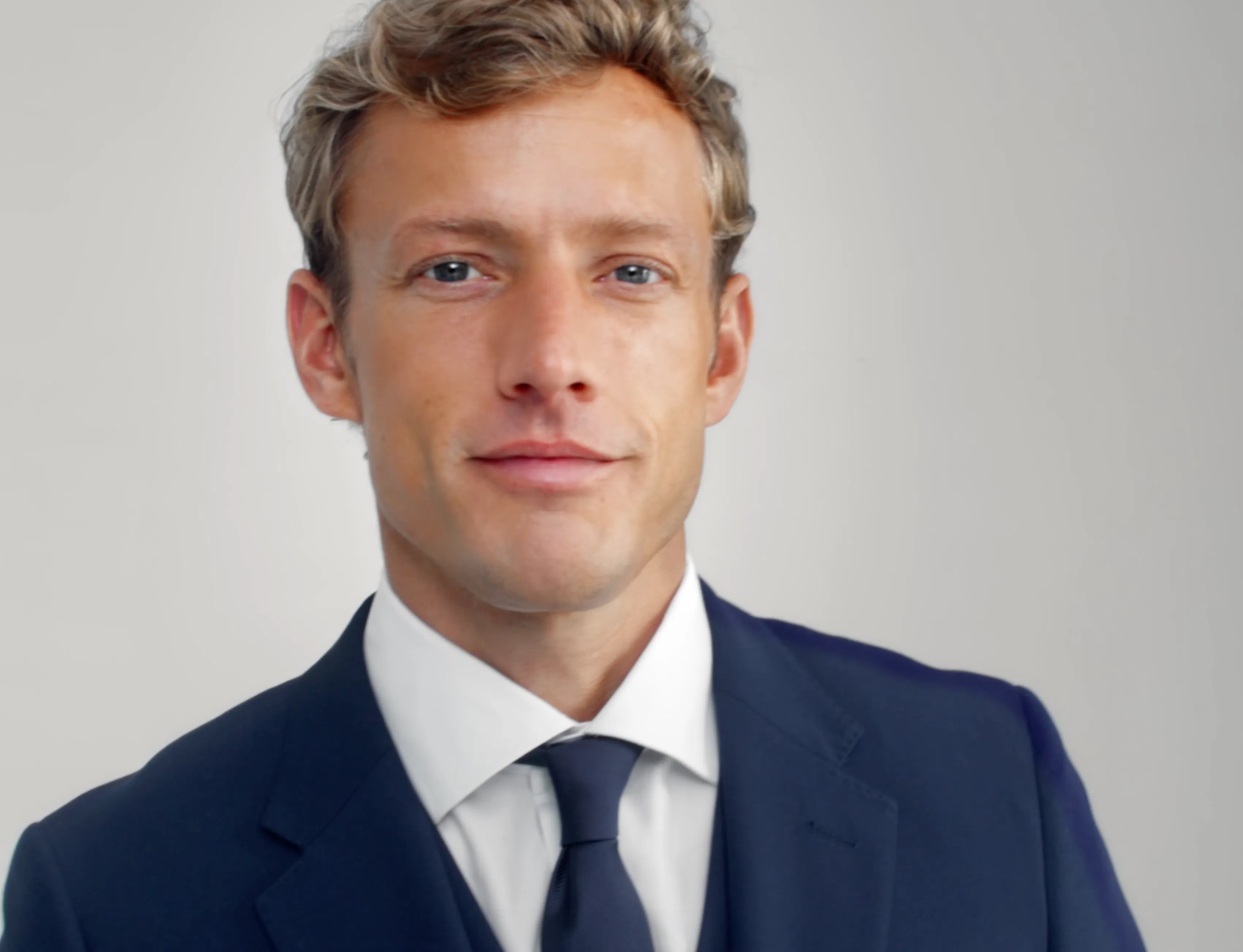 Up close of a man wearing a navy tie with a navy suit.
