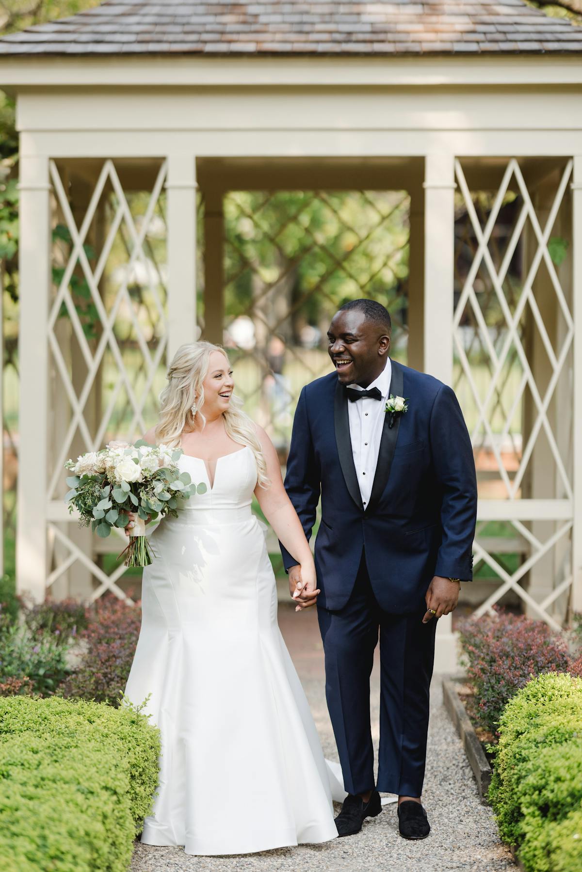 Bride walking down the aisle with groom in navy tuxedo at farmhouse chic venue as a giving away the bride alternative.
