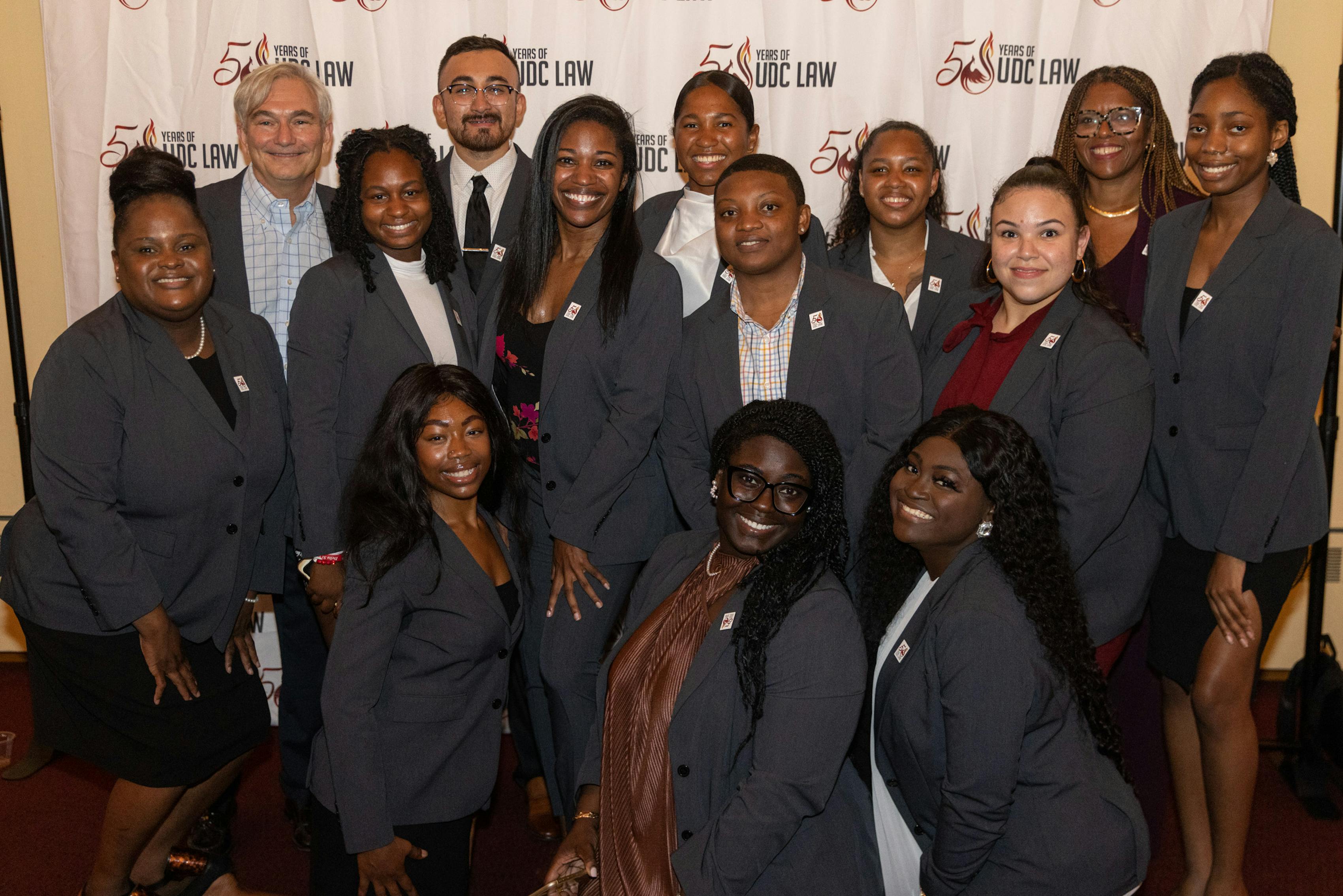 Group of law students posing in their matching professional charcoal suits for law pinning ceremony.