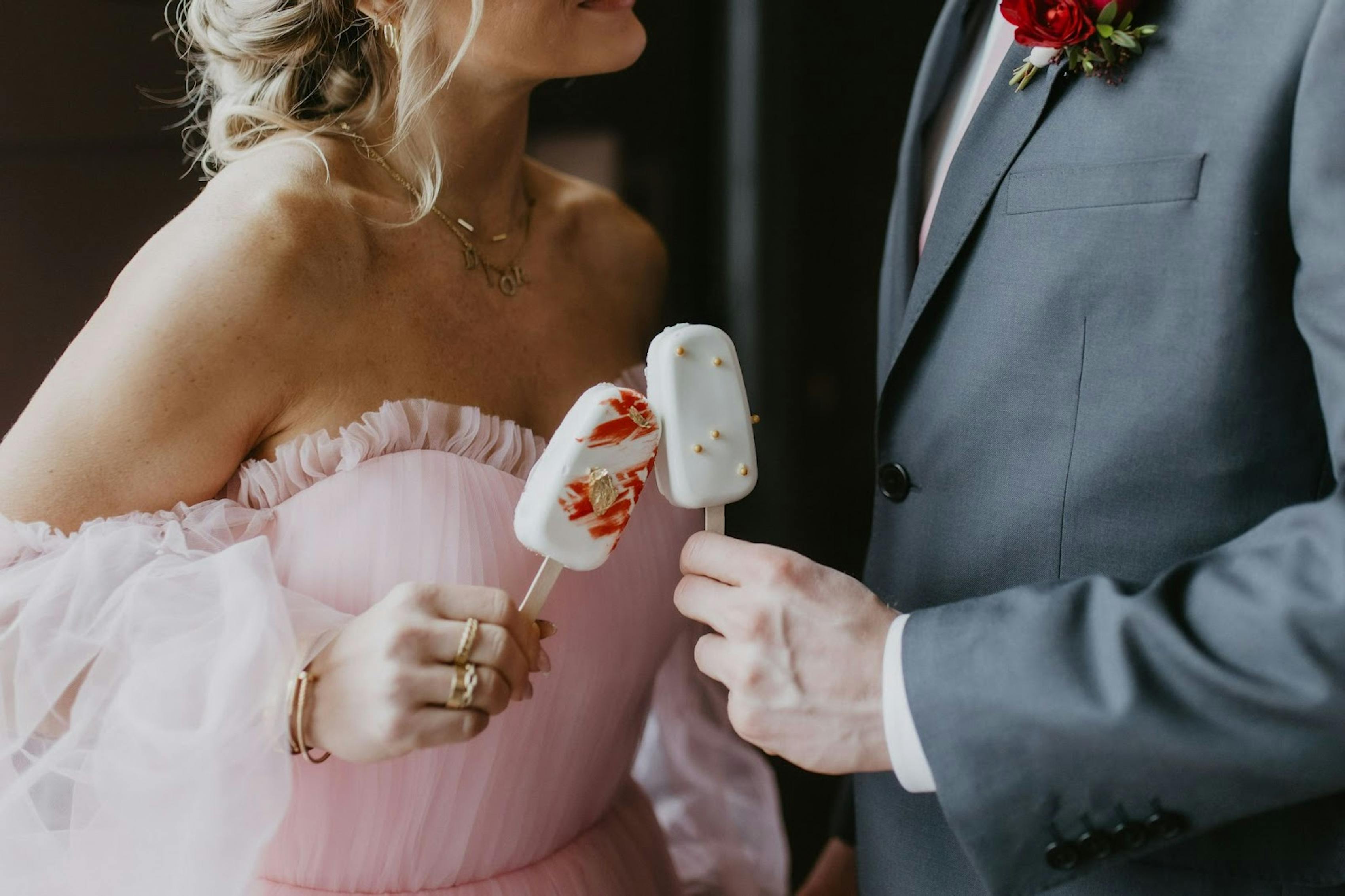 A bride's sweetheart puffsleeve pink wedding dress matched with a light gray wedding suit for the groom