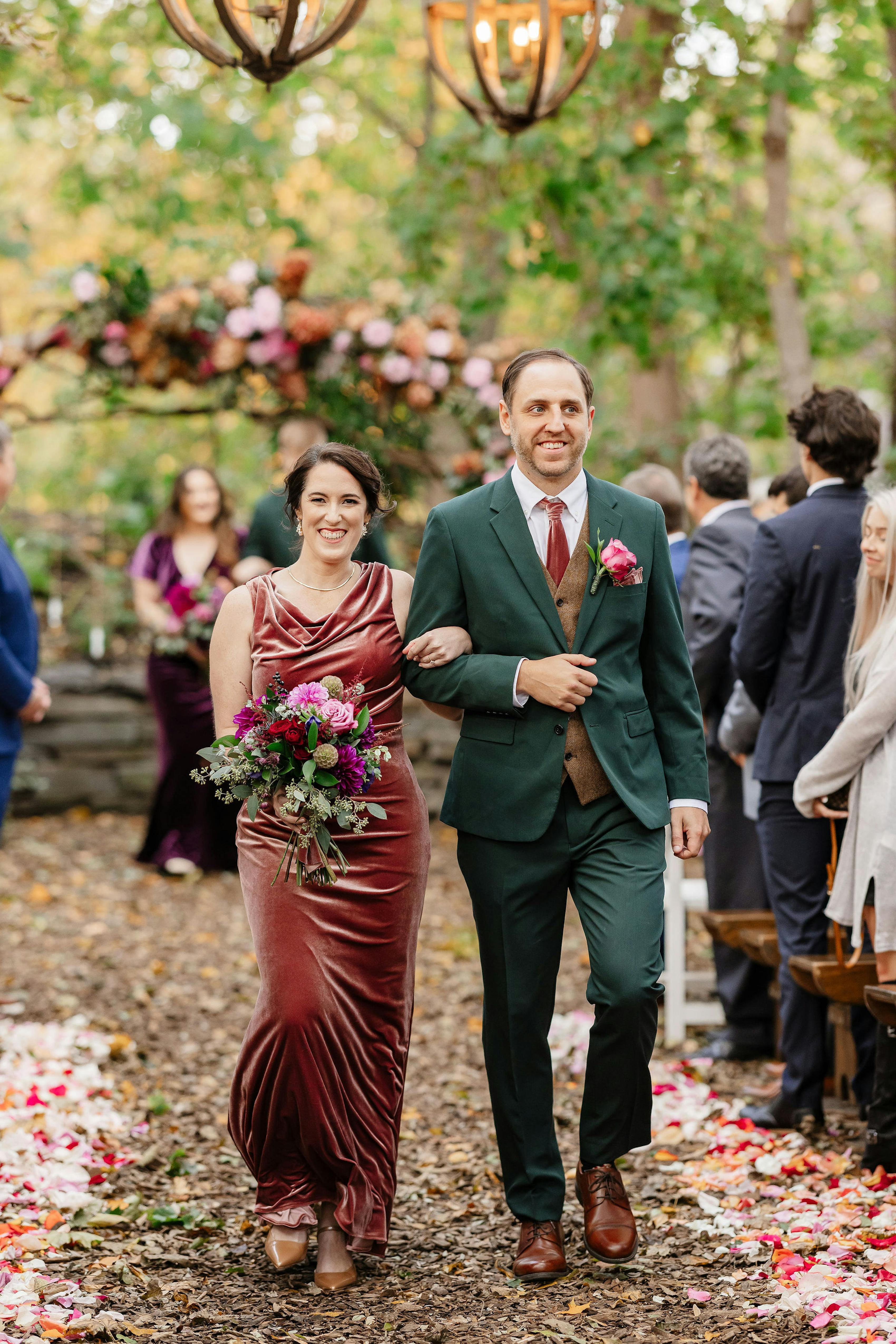 Autumn leaves wedding decor lining the aisle as groomsman and bridesmaid walk down.