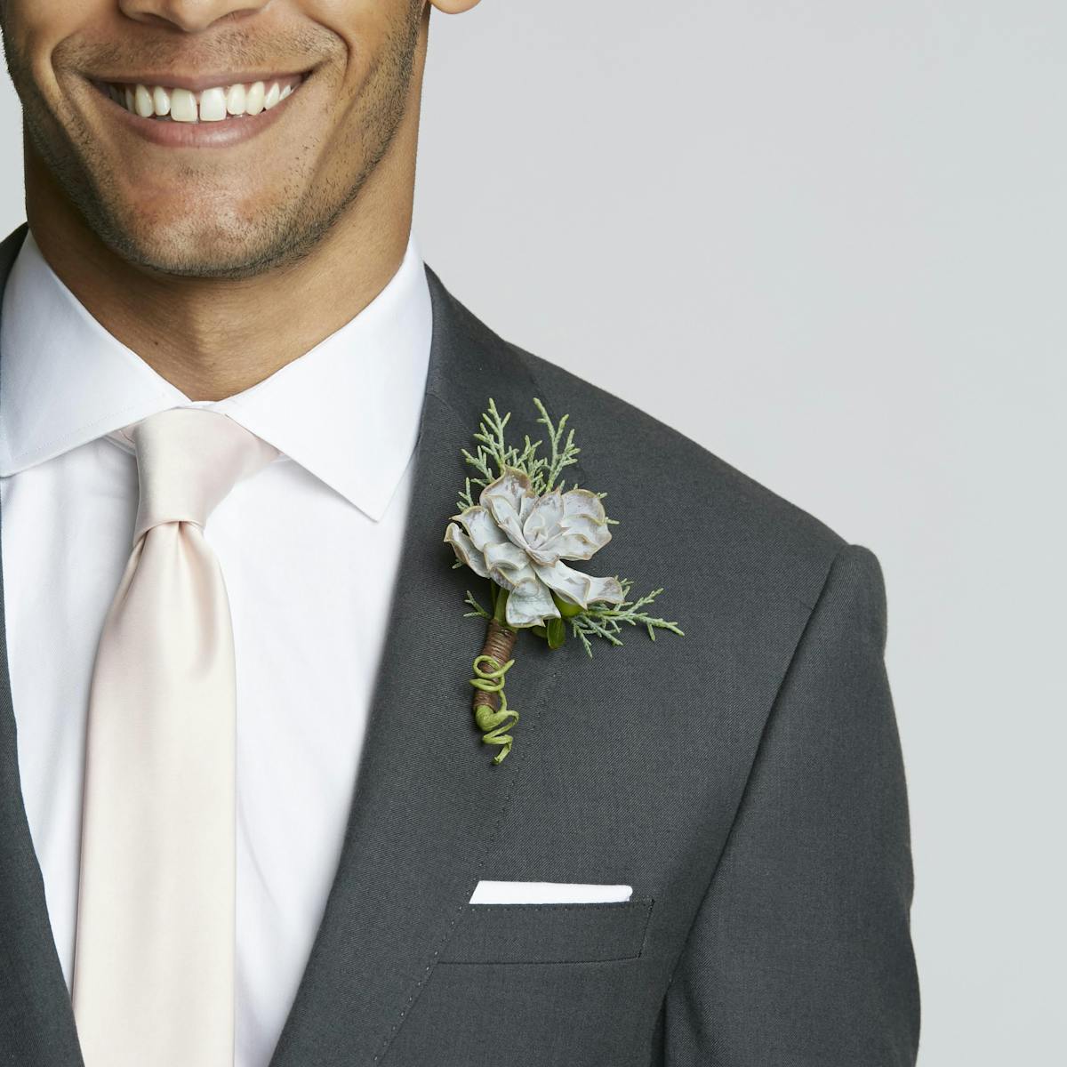 Neutral charcoal grey groomsman suit with champagne tie and succulent boutonniere.