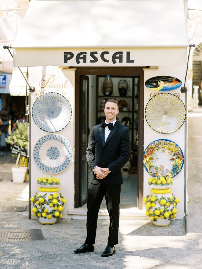 Man in destination wedding black tie style wearing a black tuxedo and bow tie at Italian wedding with lemon decor.