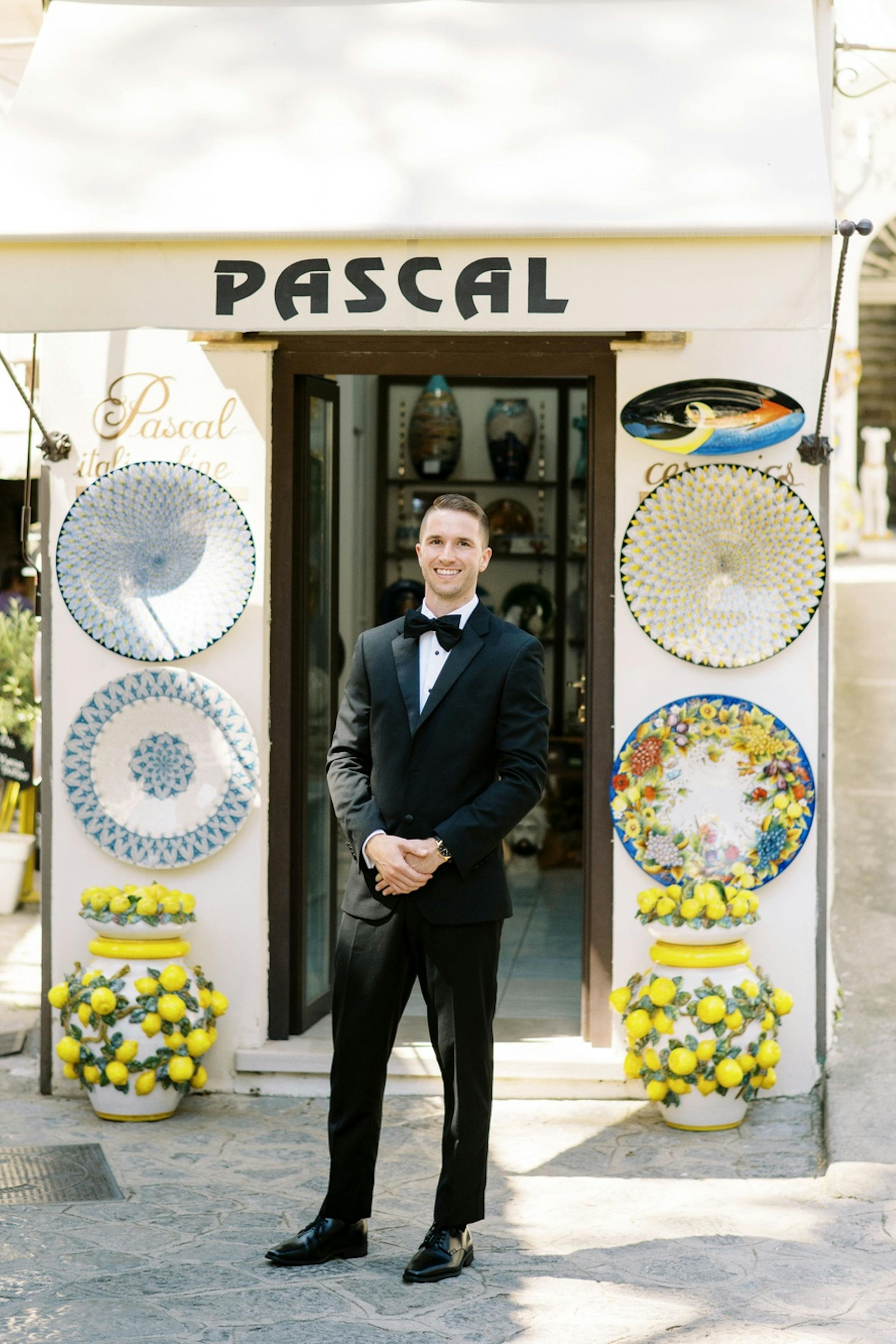 Man in destination wedding black tie style wearing a black tuxedo and bow tie at Italian wedding with lemon decor.