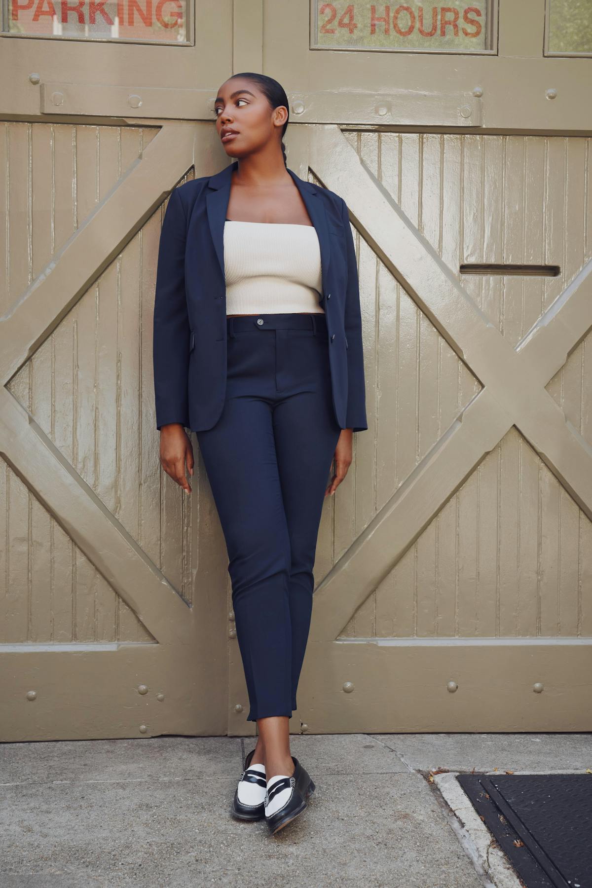 Simple power suit outfit for women with dark blue blazer and suit pants, black and white loafers, and white top to wear to the office.