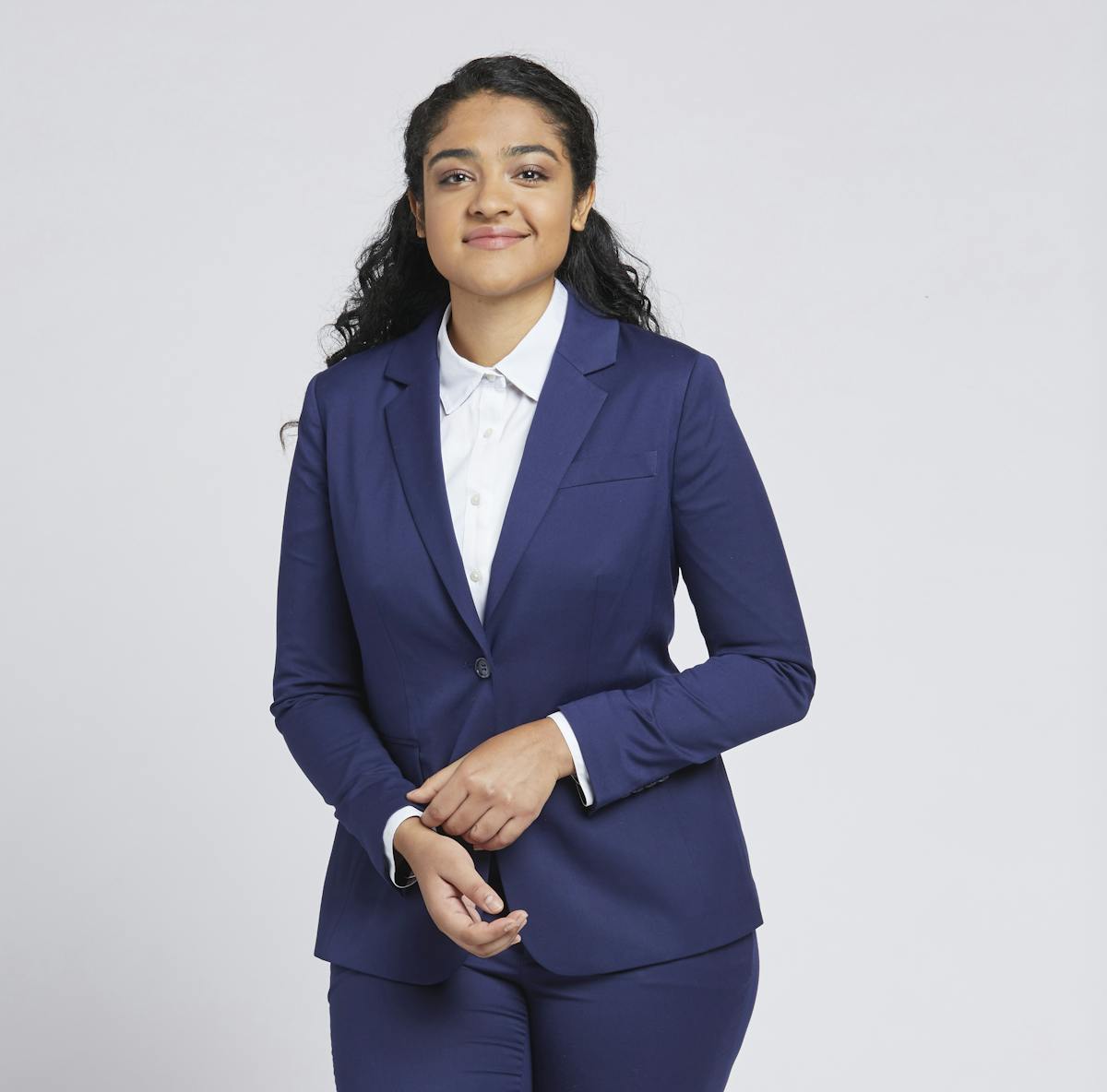 Businesswoman outfit of a lady's blue pantsuit, navy blazer, and dress pants for women paired with a white button up shirt for the office.