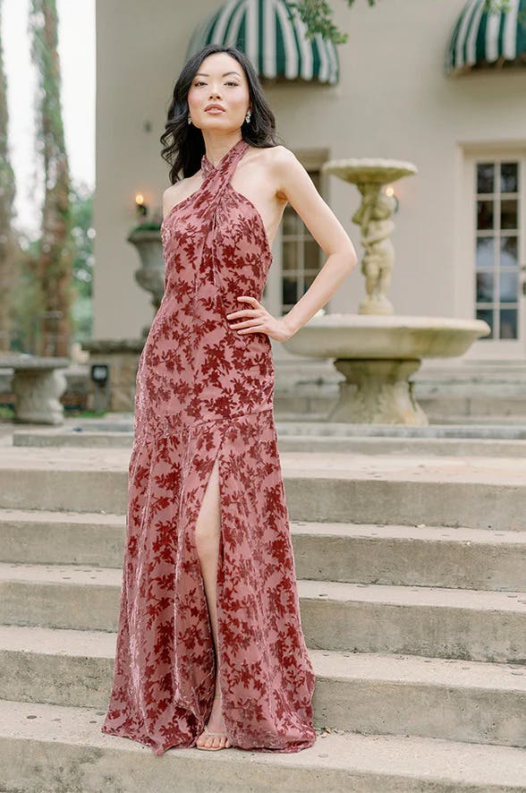Dusty rose bridesmaid dress in velvet burnout flower pattern and halter neck with leg slit.