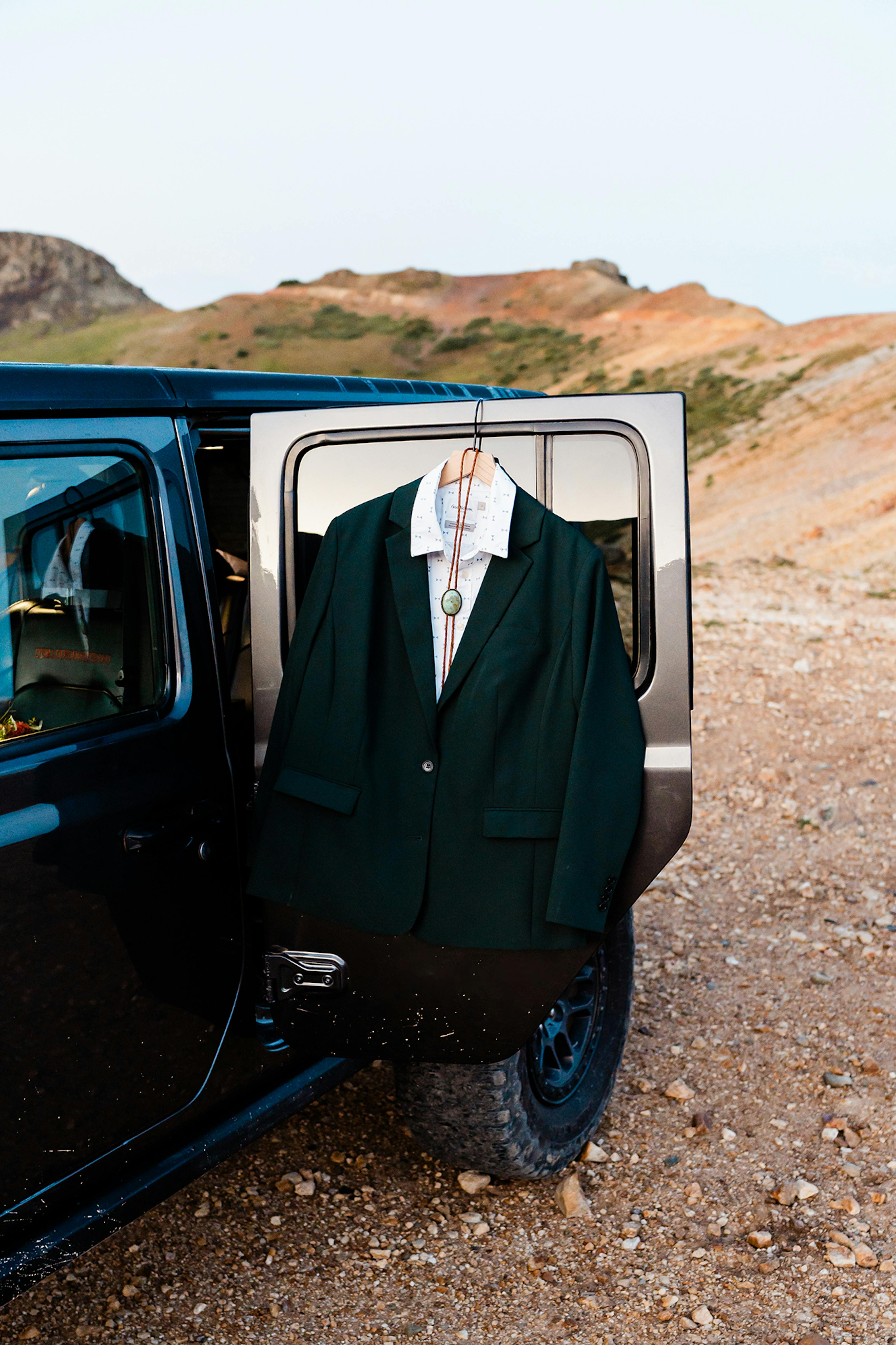 Green suit displayed on a Jeep for mountain elopement style.
