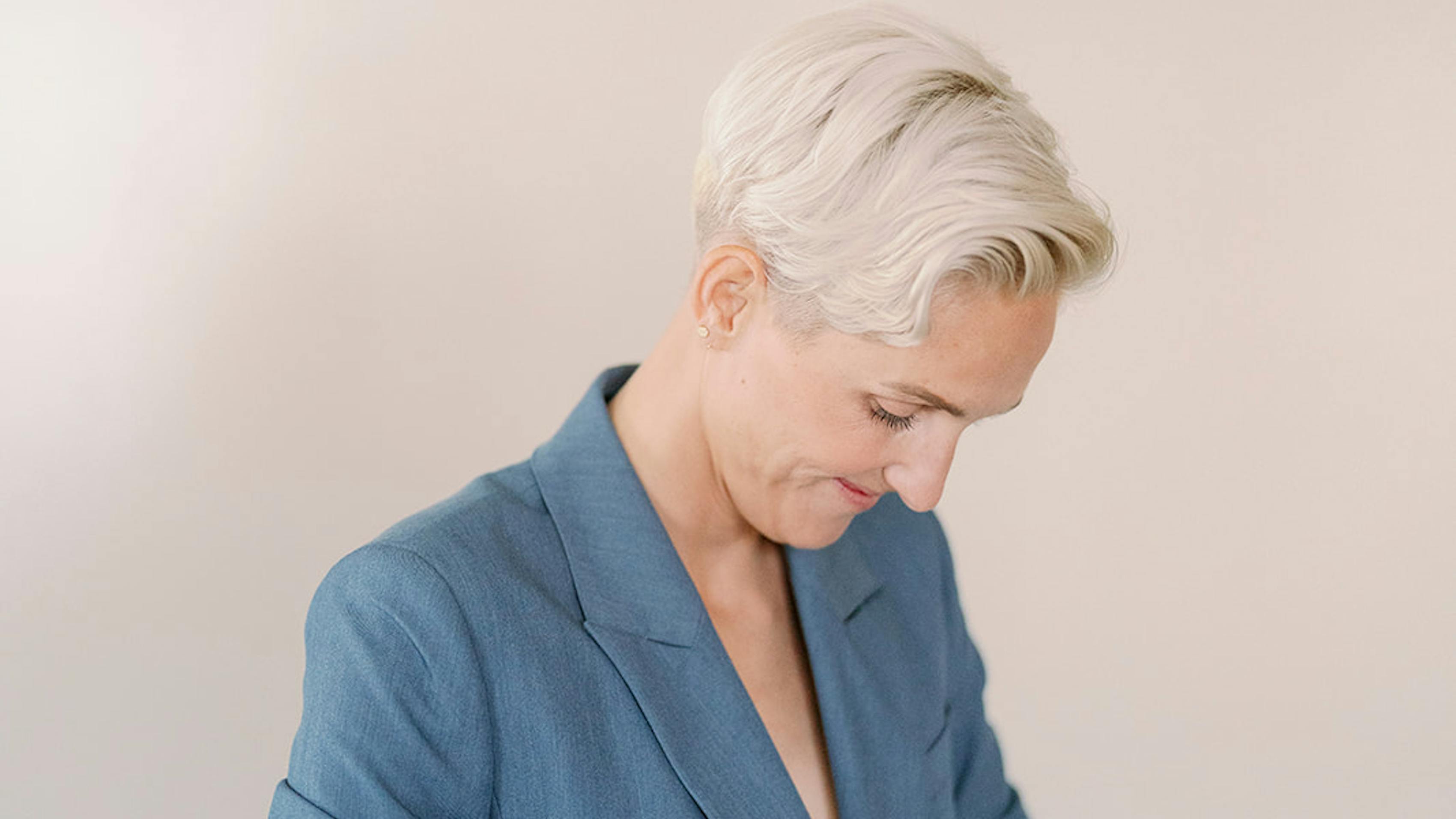 Sally Osborne buttoning her double breasted light blue suit jacket for her wedding.