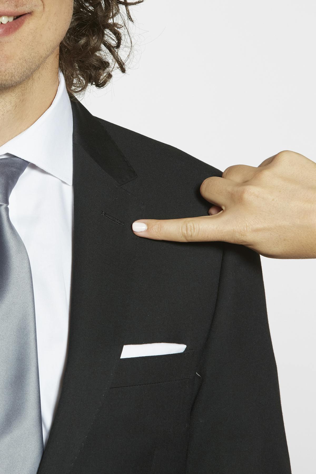 Pointing at the placement to pin a boutonniere on a notch lapel suit jacket