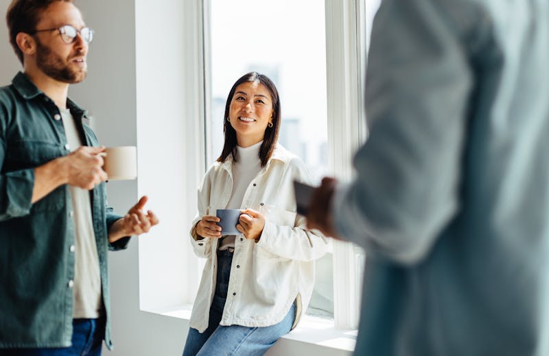sfeer impressie van iemand die koffie drinkt met collega's er omheen 

