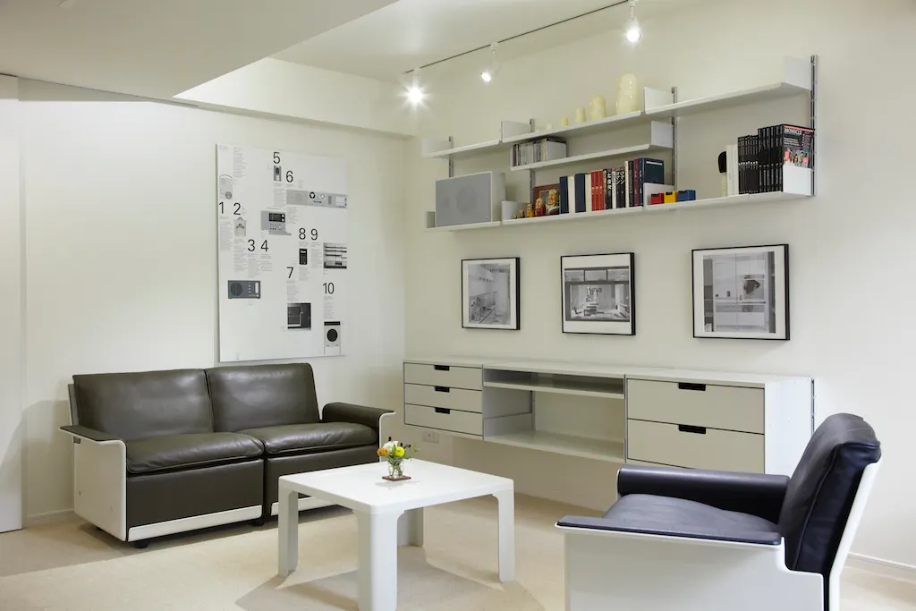 A dark leather Vitsœ 620 sofa and matching armchair sit in a Tokyo living room beside a white table.