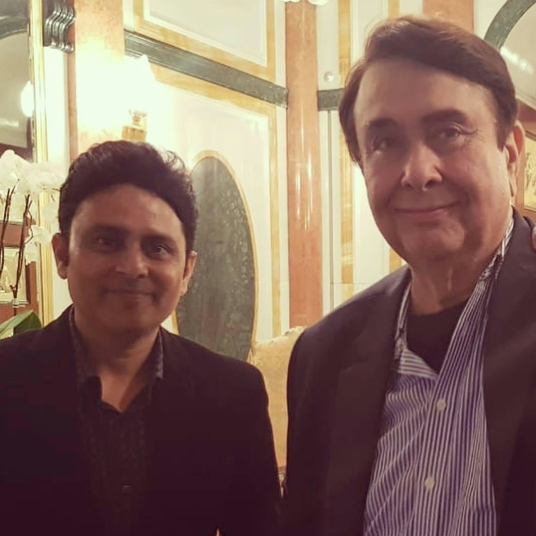 Randhir Kapoor in a blue striped shirt and dark blazer smiling next to Dr. Sundeep Kochar in a black suit.