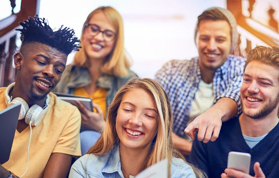 Studierende sitzen auf Treppe und halten Tablets und Smartphones