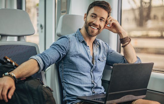 Man travelling on a train with laptop