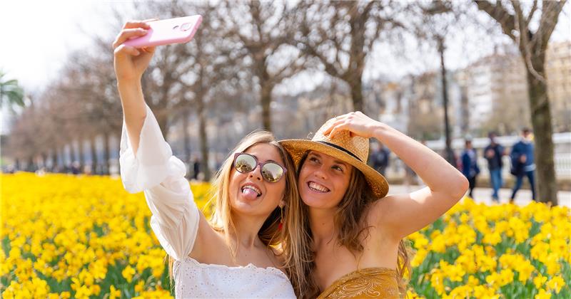 Deux femmes prennent un selfie dans un champ de fleurs jaunes.