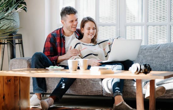 Couple sitting on a sofa looking at laptop screen