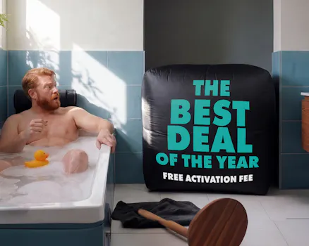 Man in bath tub looks at balloon with the writing "Best Deal of the Year"