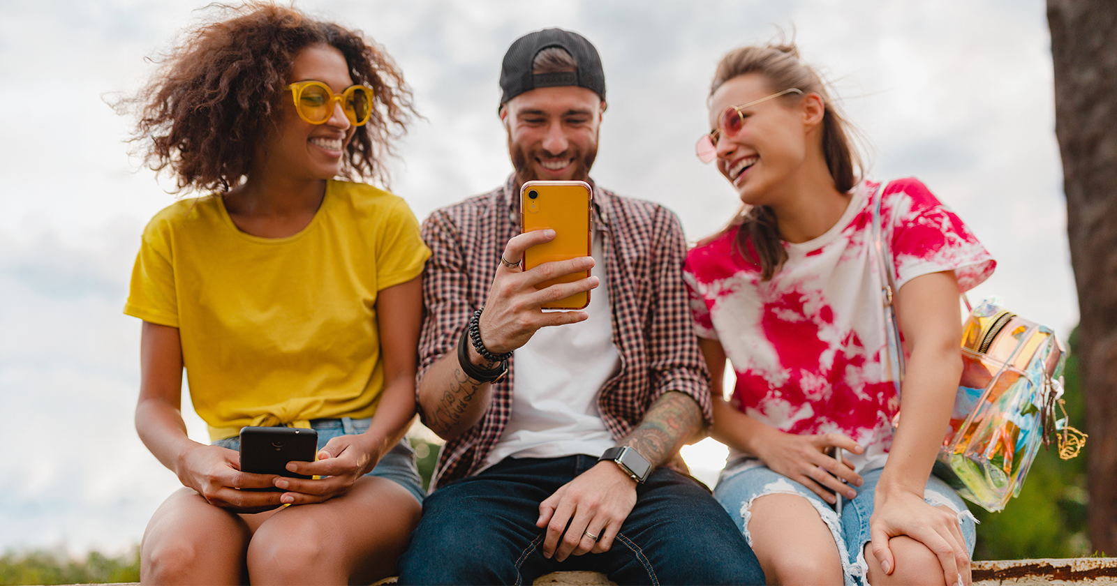 Drei Freunde lachen gemeinsam während sie auf ein Handy schauen – sie teilen einen unvergesslichen yallo-Moment