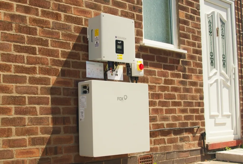 a white battery and inverter on a brick wall, near a white door