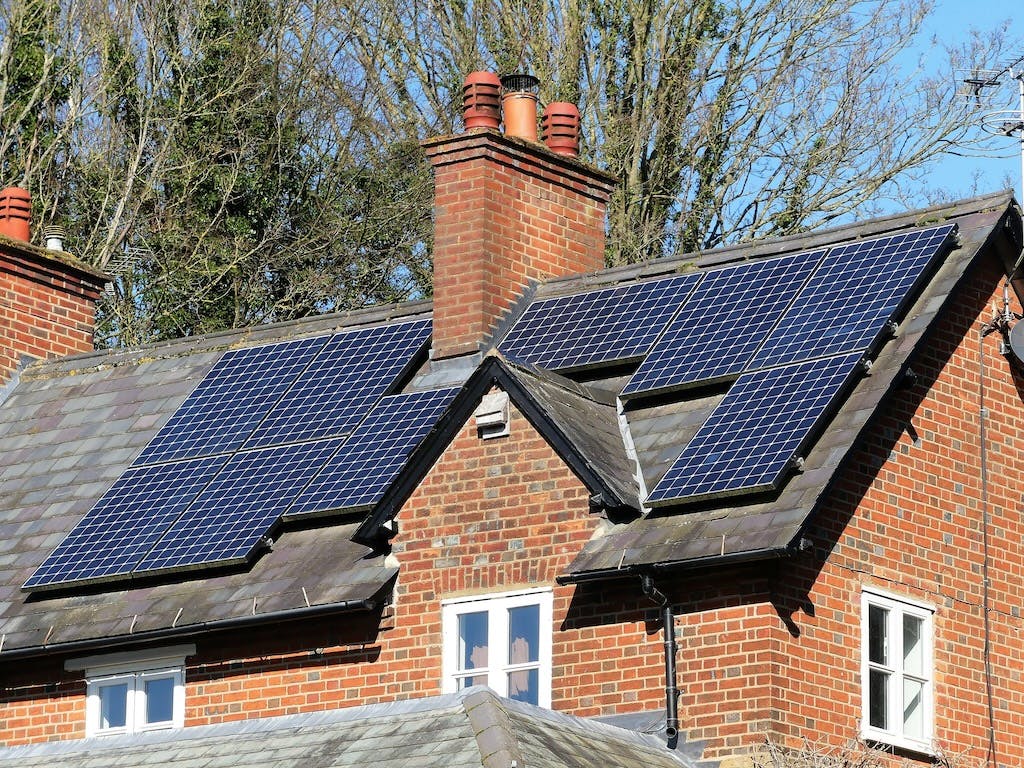 A solar panel array on a rooftop in the UK, trees in the background, blue sky