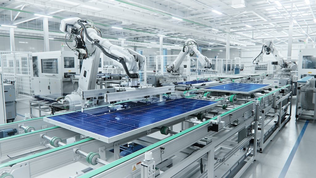 Blue polycrystalline solar panels being produced in a factory by automated machinery
