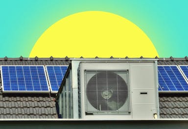 A heat pump and solar panels on a grey roof under a sun and an aquamarine sky