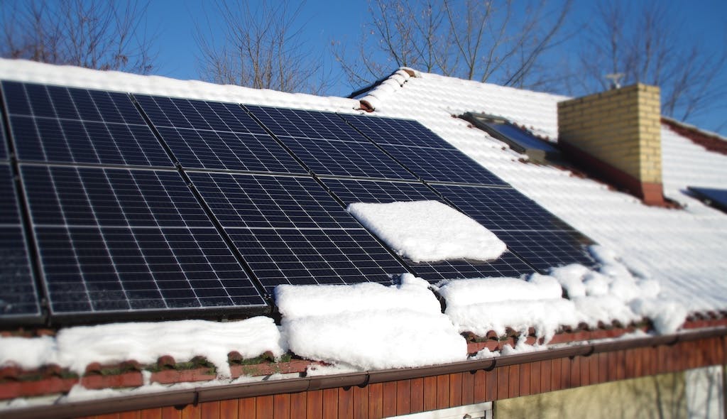 Snow sliding off a solar panel system on a rooftop in winter