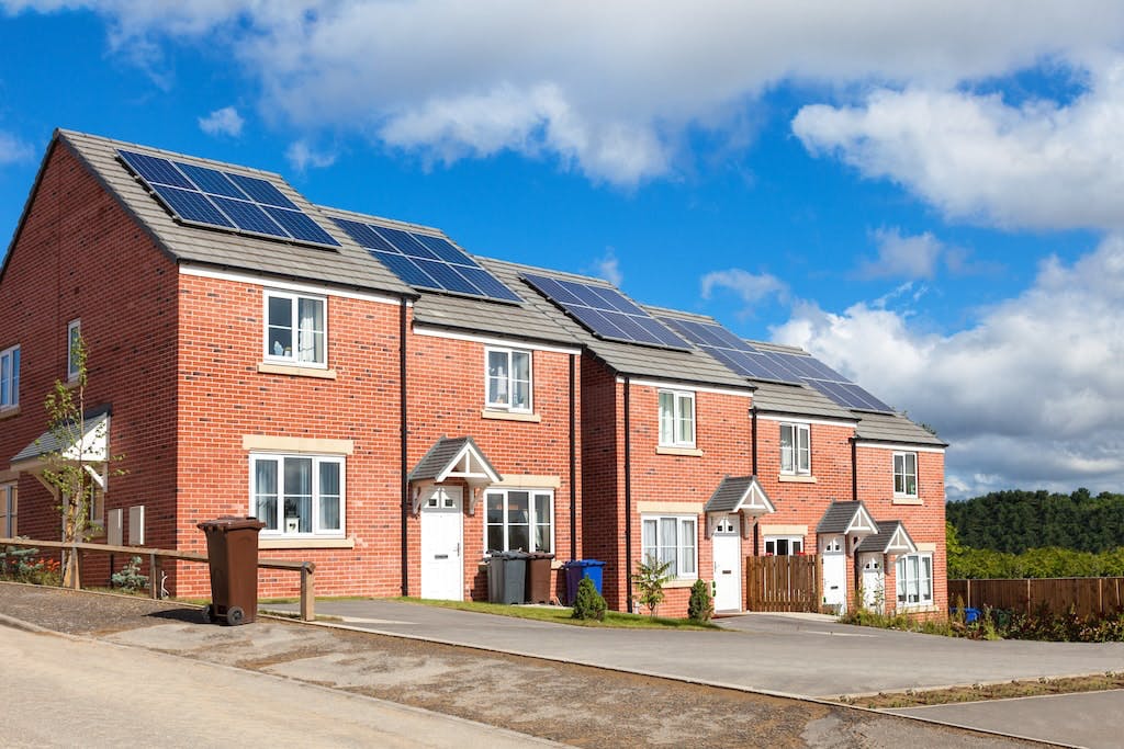 A row of red houses in the UK with solar panels on each rooftop