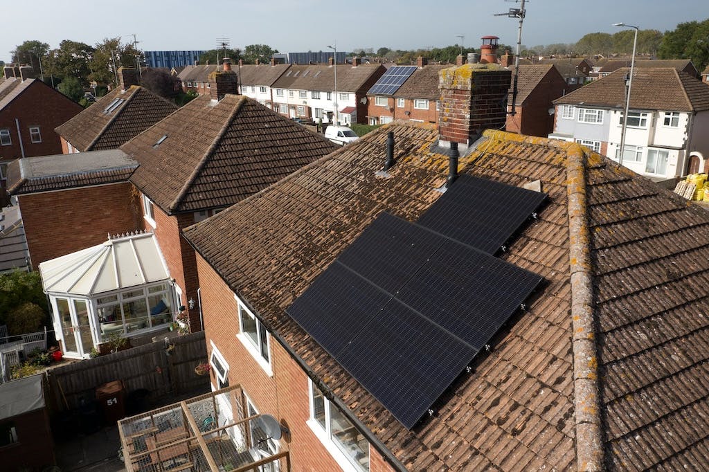 An array of black solar panels on a UK rooftop, other houses in the background