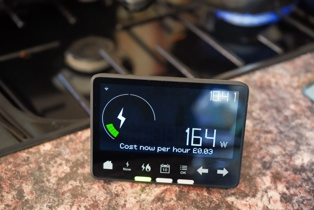 A smart meter's digital display screen on a kitchen worktop, beside a gas hob