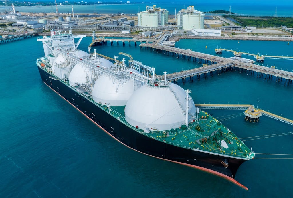 Liquefied Natural Gas (LNG) tanker anchored in gas terminal on a dark blue body of water