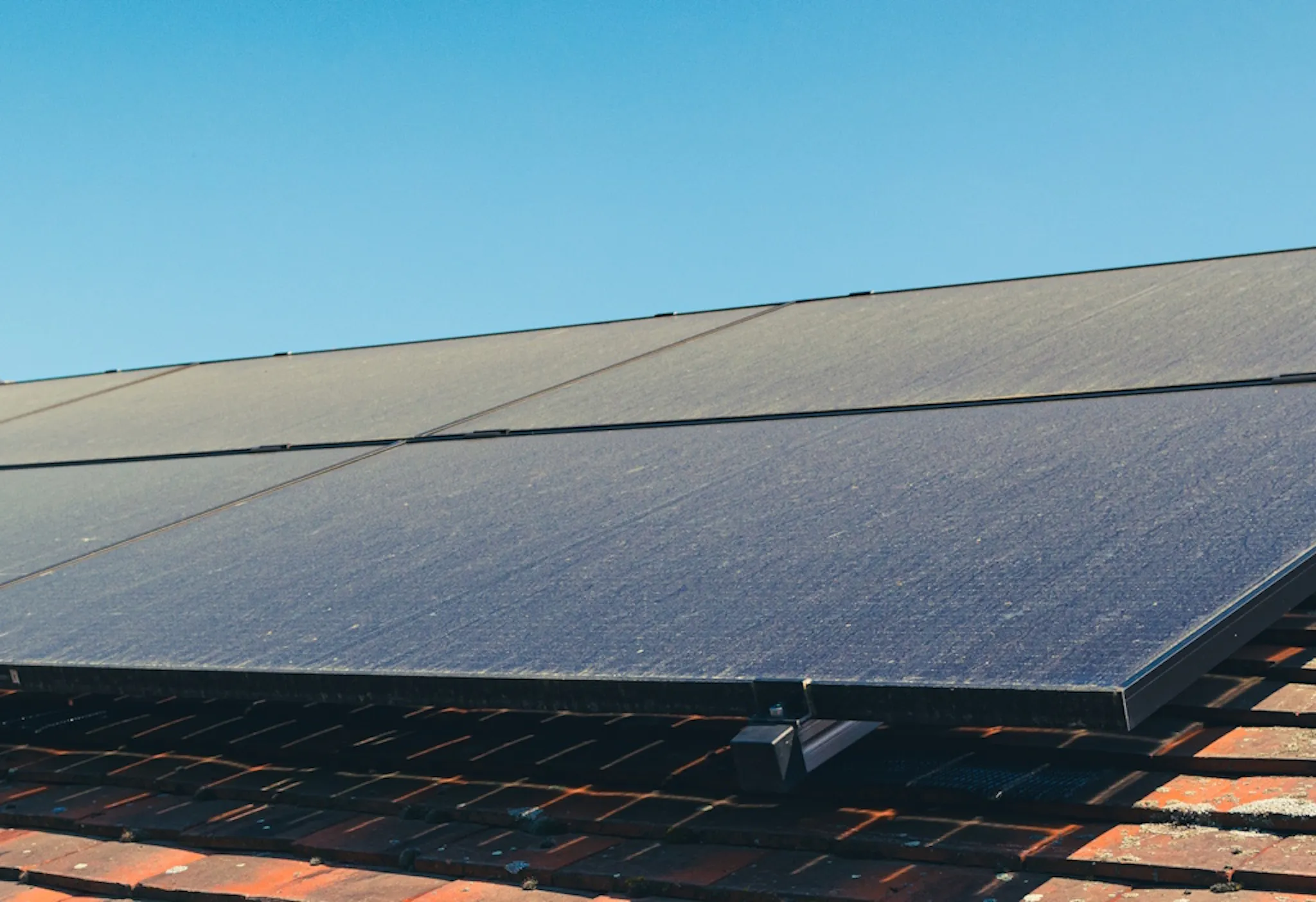 dusty black solar panels on a terracotta roof