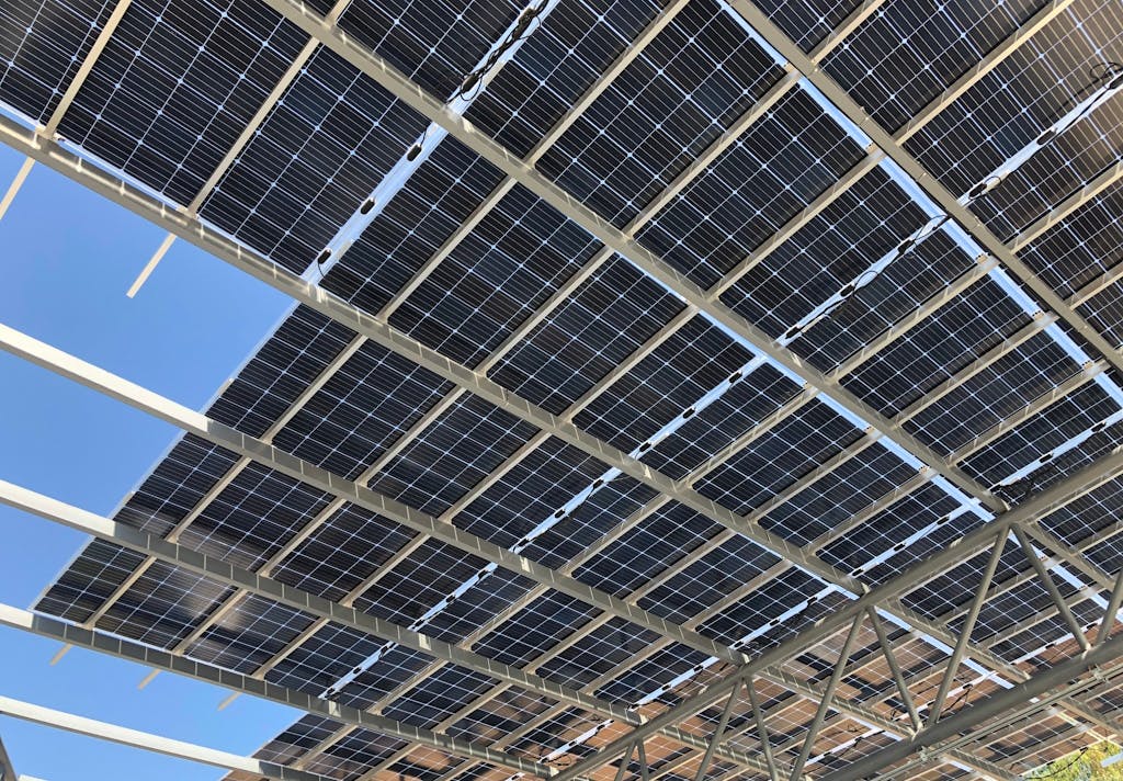 Black bifacial solar panels on a roof, under a blue sky