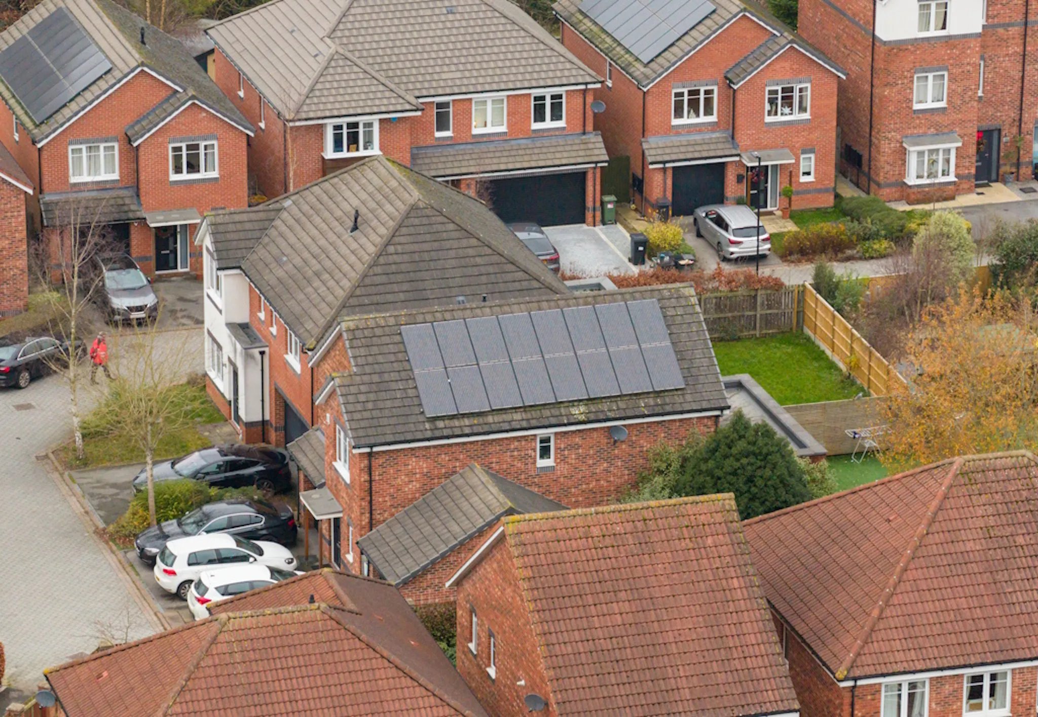several red-brick houses, two with black solar panels on their roofs