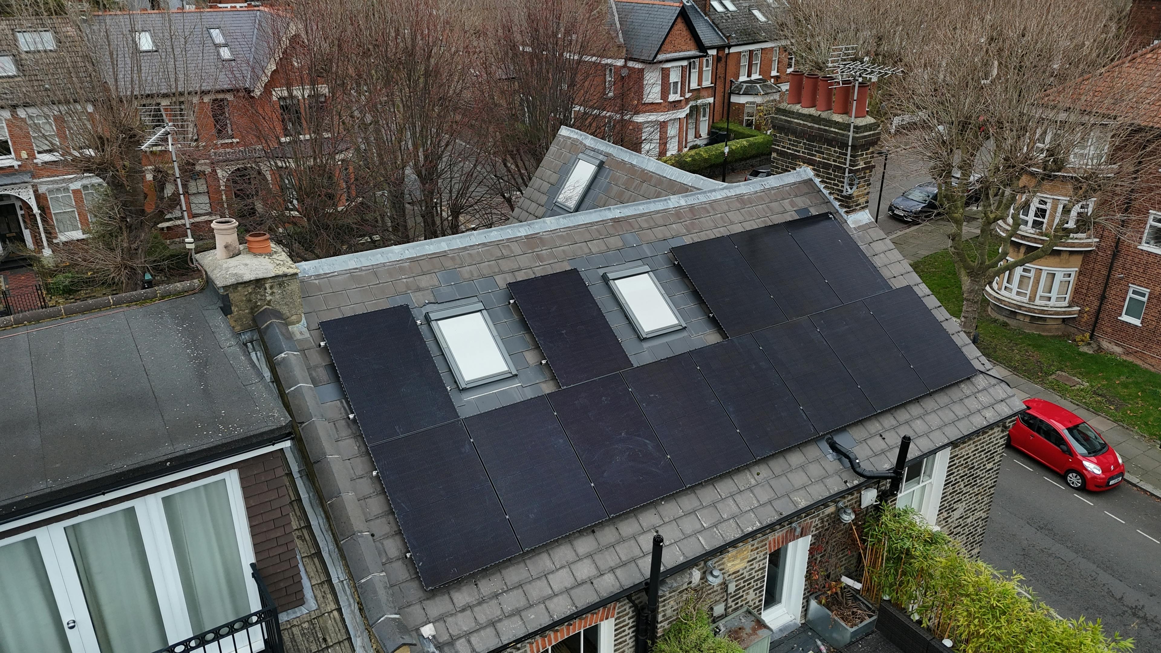 Black solar panels on a grey roof, arranged around two skylights