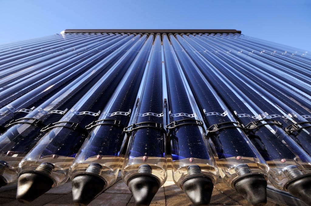 Close up shot of the evacuated tubes of a solar thermal panel, blue sky in background