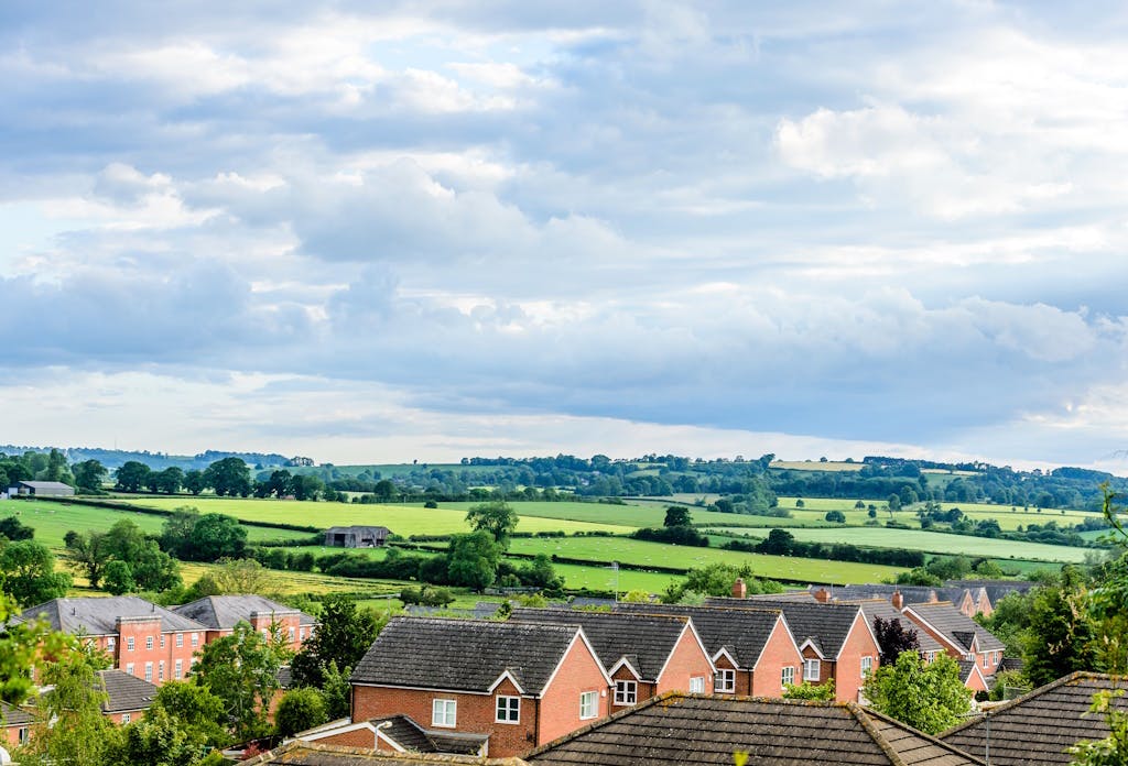 a series of terracotta houses set against a background of rolling green hills, under a cloudy sky