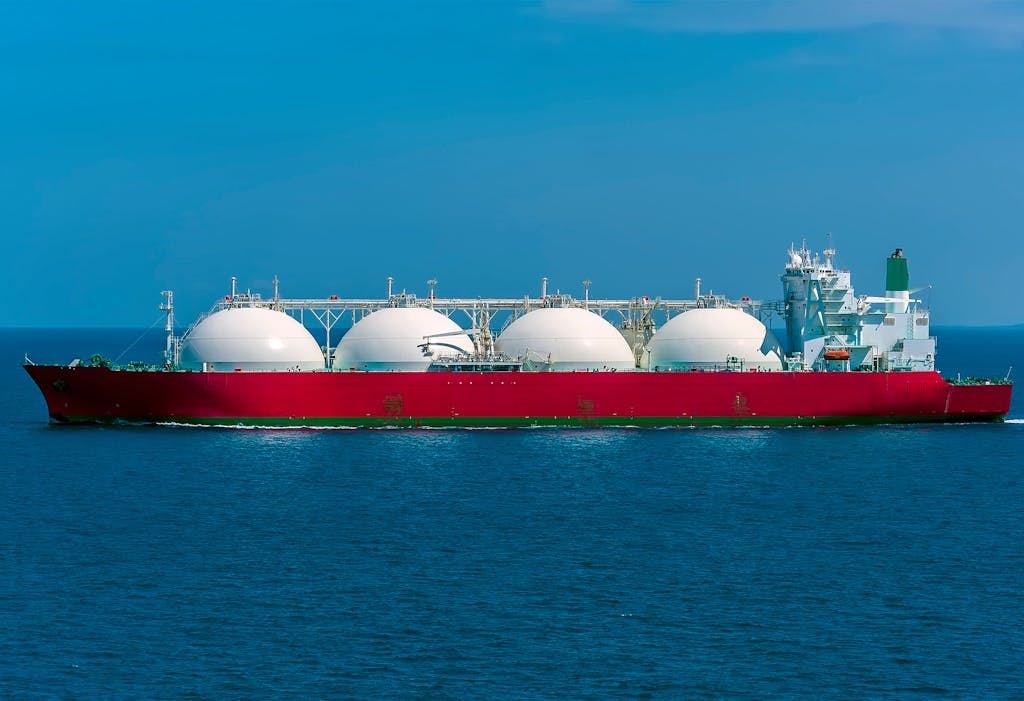 a red LNG tanker on the ocean, under a blue sky