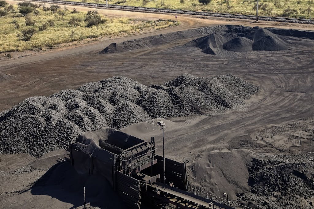 Large piles of processed Manganese ore rock in front of trees