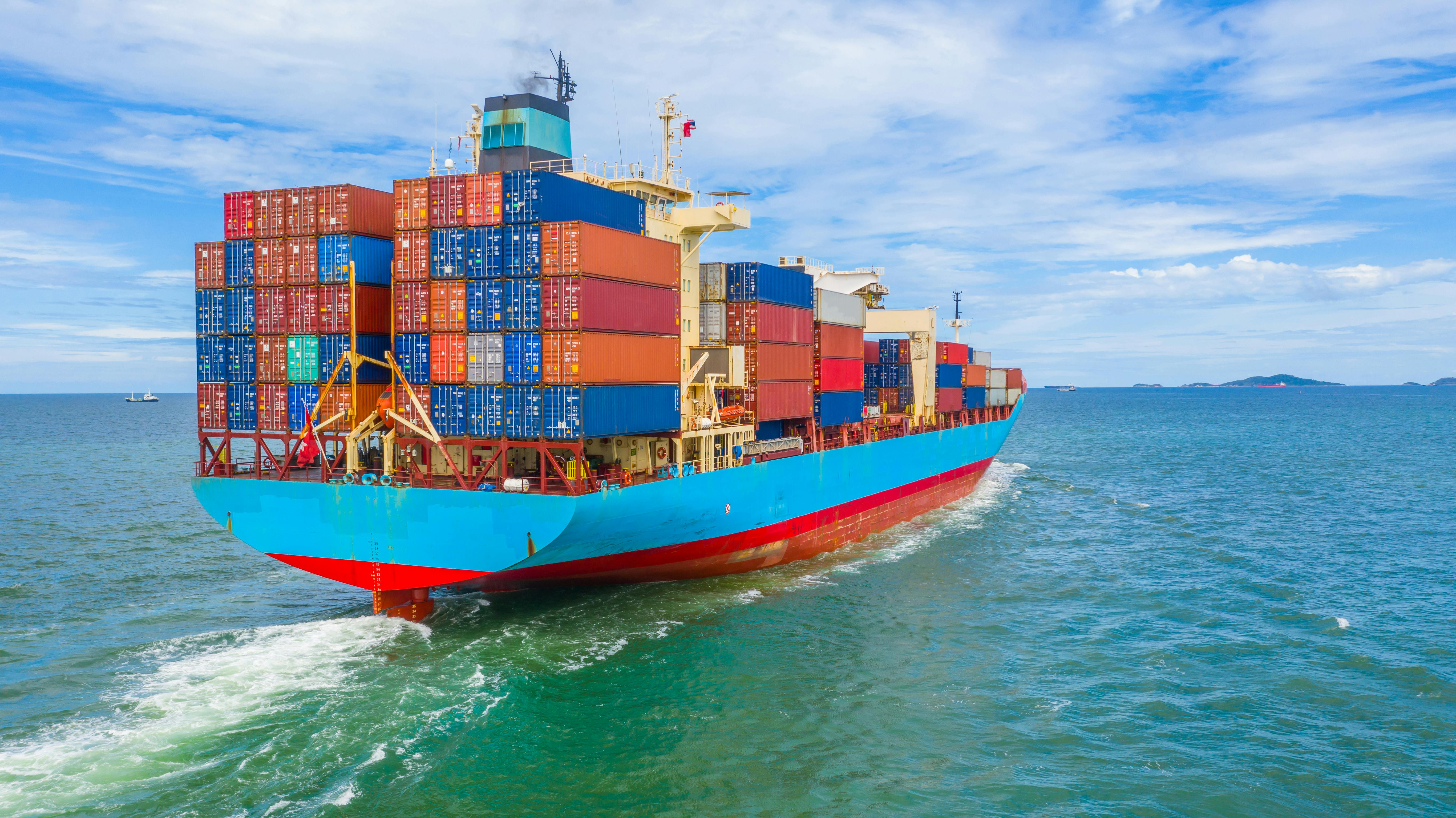 Full container ship on the open ocean, under a blue sky