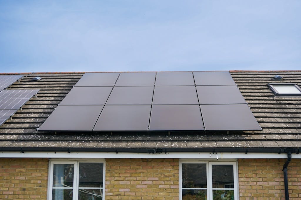 Black solar panels on a dark roof, under a light blue sky