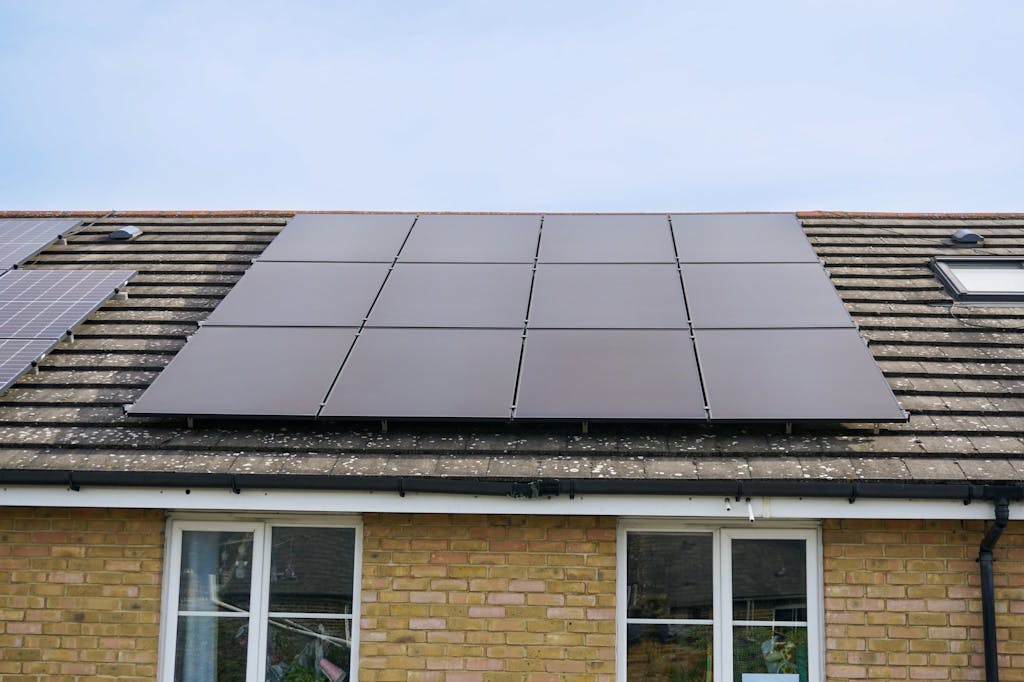 Black solar panels on a grey roof, under a light blue sky